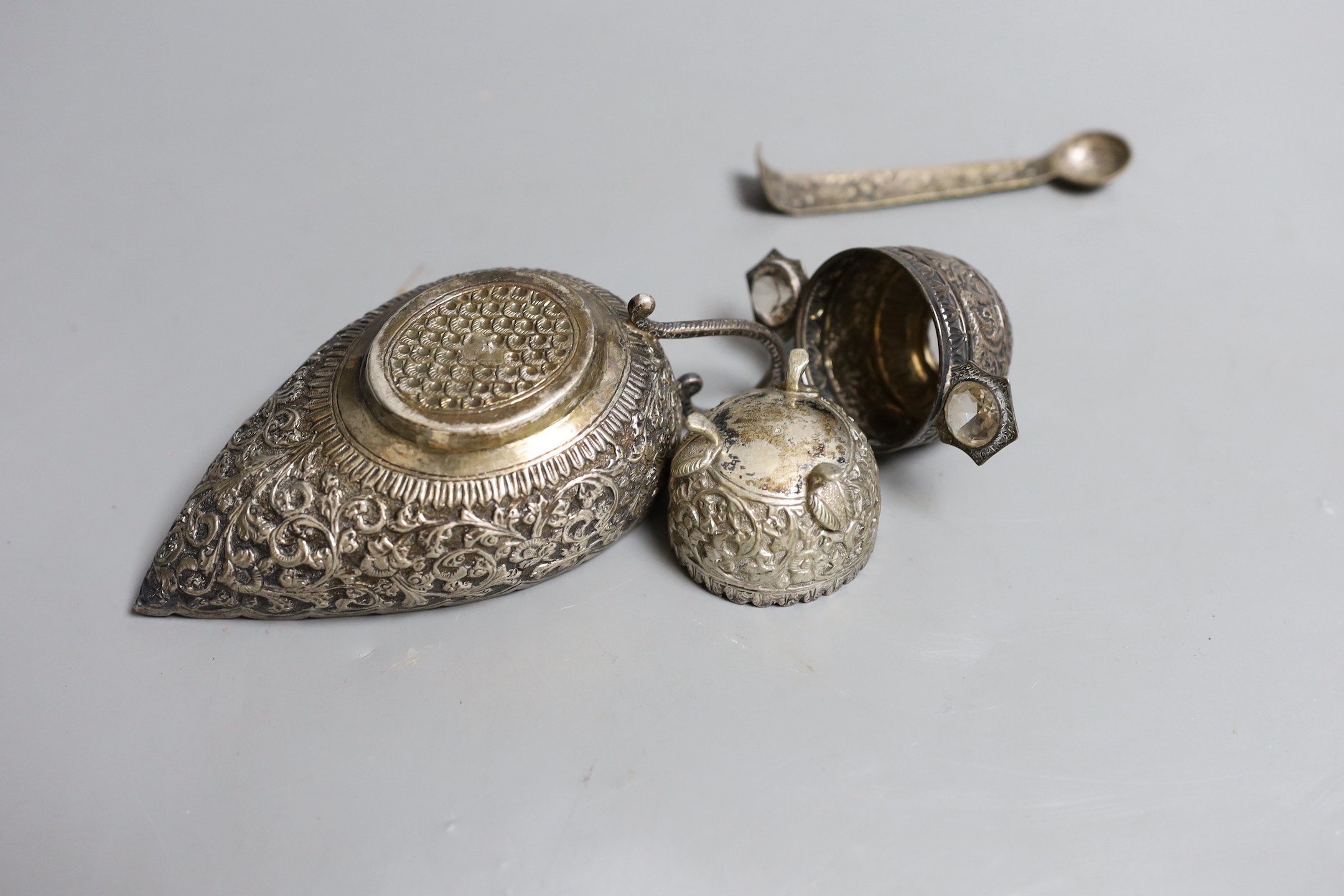 An Indian white metal gem set tasting cup, diameter 87mm, a sauce boat, salt and part of a pair of tongs (a.f.).